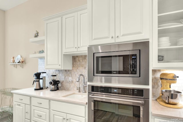 kitchen with tasteful backsplash, stainless steel appliances, sink, and white cabinets