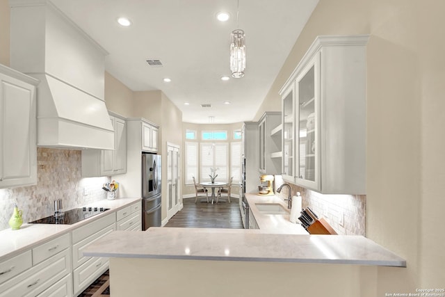 kitchen with sink, white cabinetry, black electric stovetop, decorative light fixtures, and kitchen peninsula