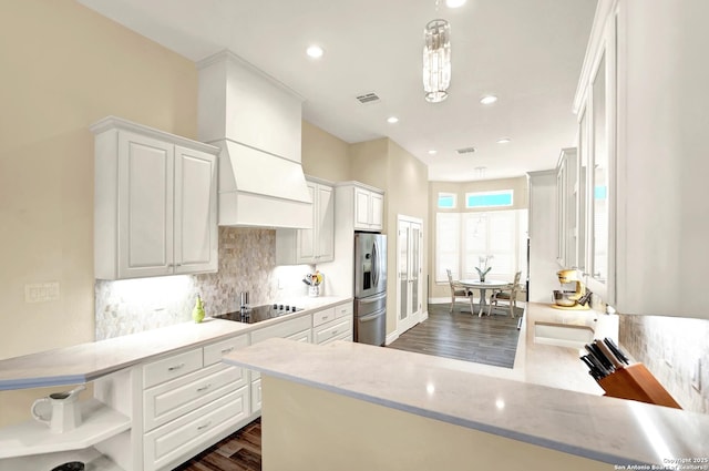 kitchen featuring white cabinetry, stainless steel fridge, decorative light fixtures, and kitchen peninsula