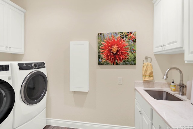 clothes washing area featuring separate washer and dryer, sink, and cabinets