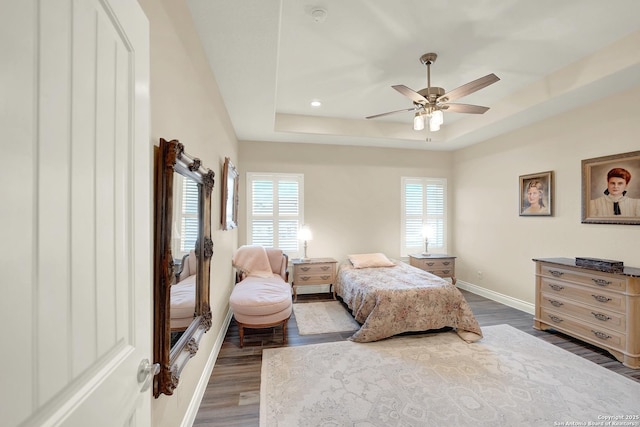 bedroom featuring dark hardwood / wood-style flooring, a raised ceiling, and ceiling fan