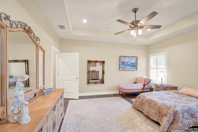 bedroom featuring dark wood-type flooring, a raised ceiling, and ceiling fan