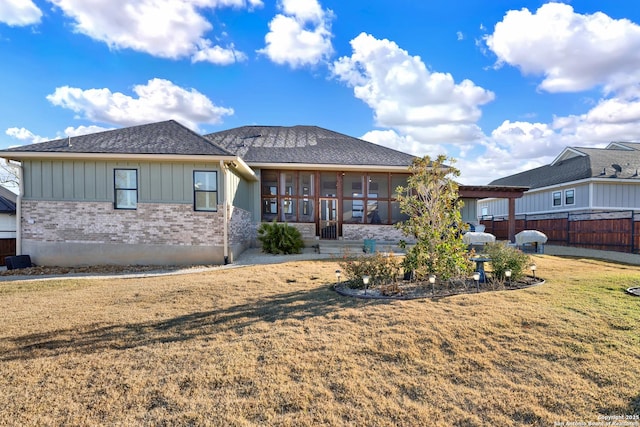 rear view of property featuring a sunroom and a lawn