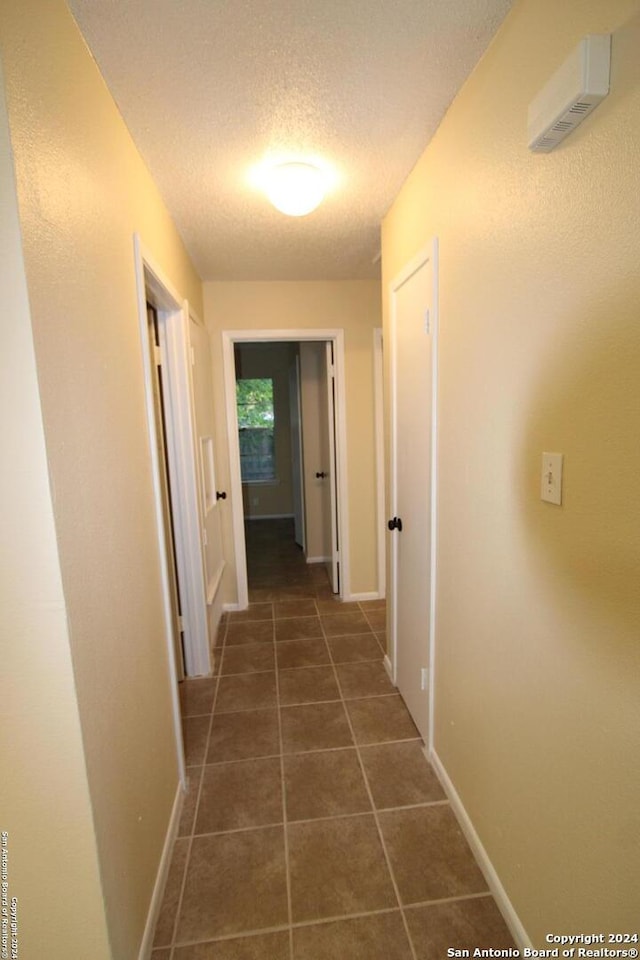 hall with dark tile patterned floors and a textured ceiling