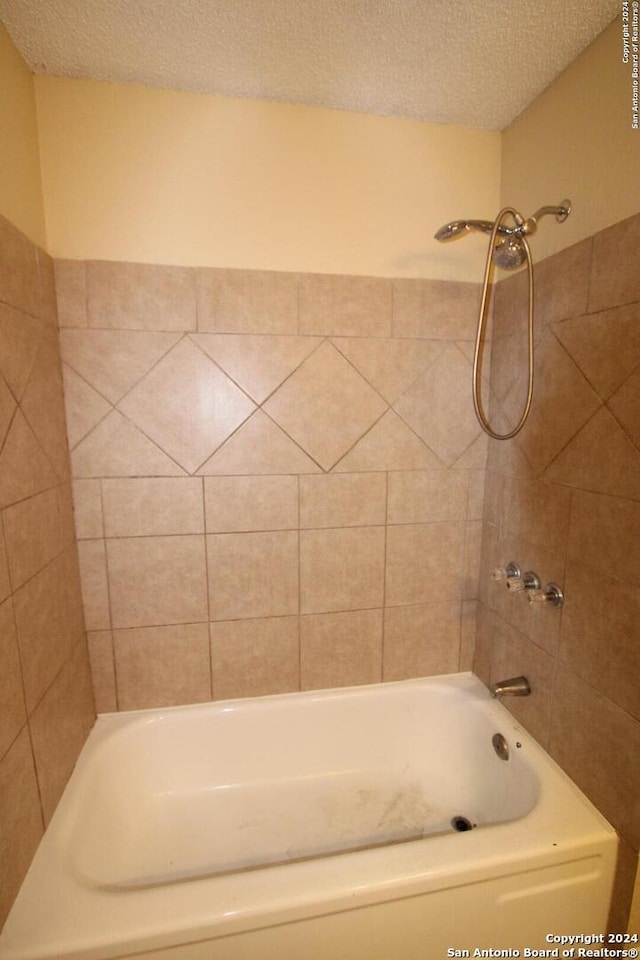 bathroom with tiled shower / bath and a textured ceiling