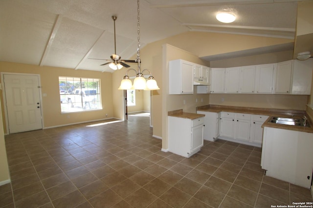 kitchen with vaulted ceiling, white cabinetry, sink, dark tile patterned floors, and ceiling fan