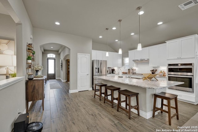 kitchen with white cabinetry, stainless steel appliances, a breakfast bar, and light stone countertops