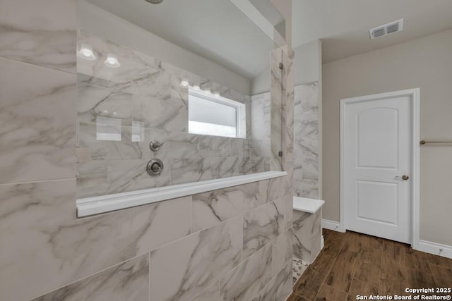 bathroom featuring a tile shower and hardwood / wood-style floors