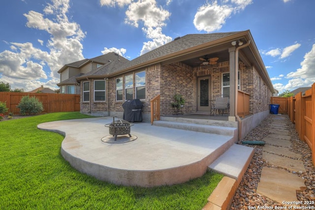 back of property with a yard, a patio area, ceiling fan, and a fire pit