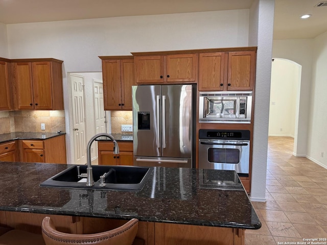 kitchen featuring tasteful backsplash, stainless steel appliances, a kitchen bar, and sink