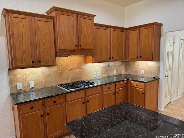 kitchen with tasteful backsplash, stainless steel gas cooktop, and dark stone countertops