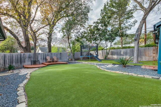 view of yard with a trampoline and a deck