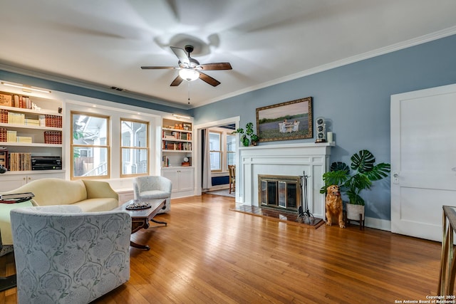 living room featuring ornamental molding, built in features, ceiling fan, and light wood-type flooring