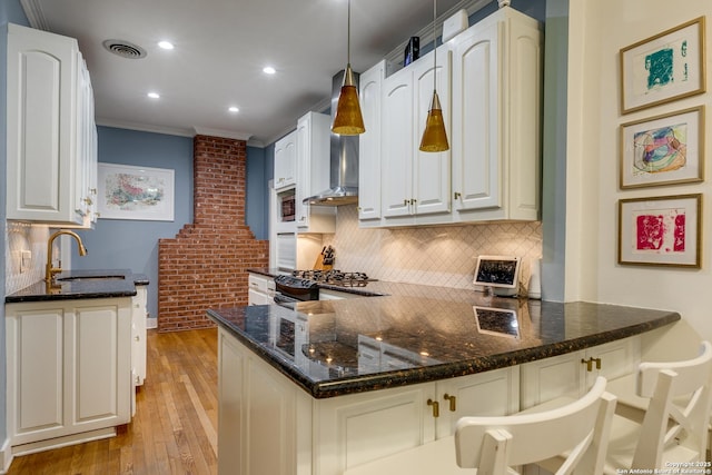 kitchen featuring white cabinetry, decorative light fixtures, kitchen peninsula, and sink