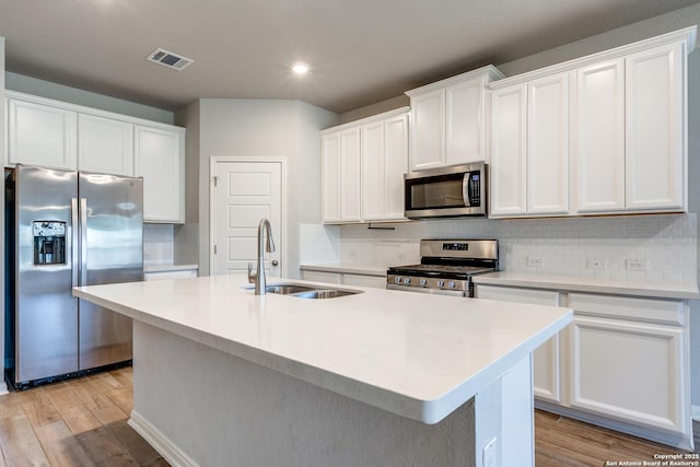 kitchen featuring appliances with stainless steel finishes, sink, a kitchen island with sink, and white cabinets