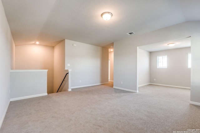 unfurnished room with light colored carpet and lofted ceiling