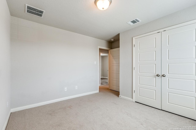 unfurnished bedroom with light colored carpet and a closet