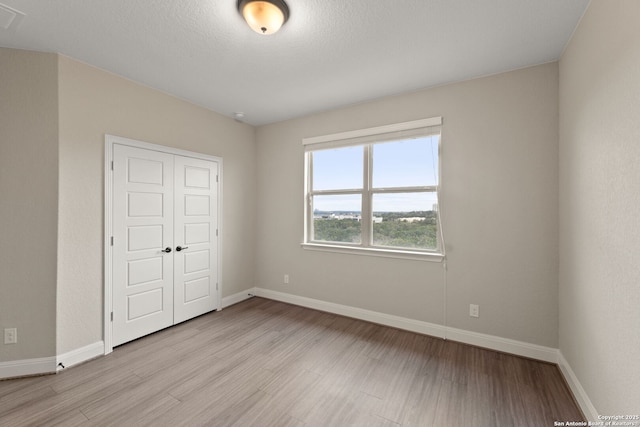 unfurnished bedroom with light hardwood / wood-style floors and a closet