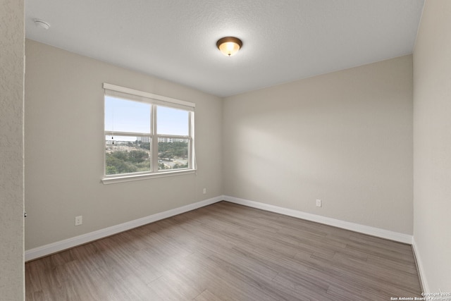 empty room with wood-type flooring and a textured ceiling