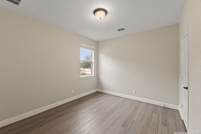 spare room featuring a textured ceiling and light wood-type flooring