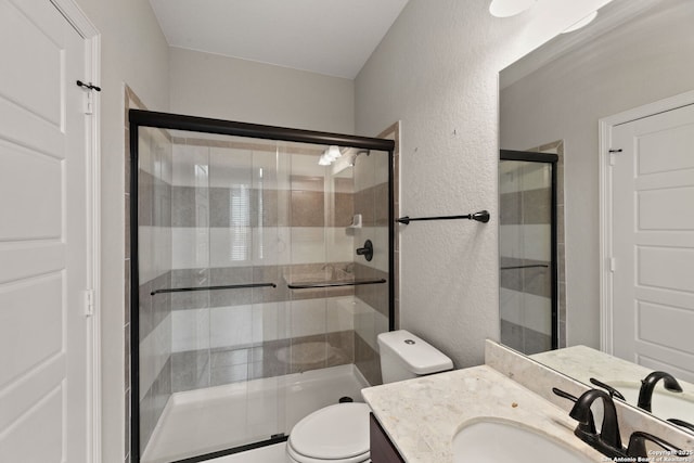 bathroom with a shower with door, vanity, and toilet