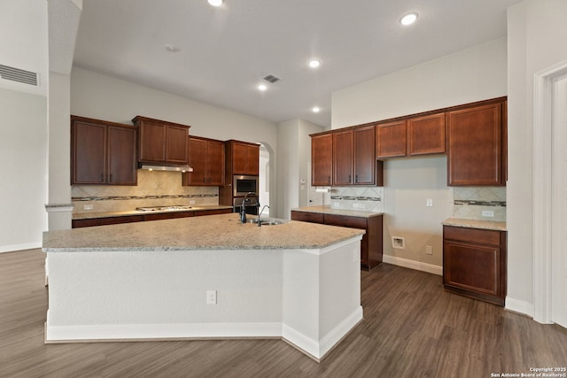 kitchen featuring sink, light stone countertops, a center island with sink, dark hardwood / wood-style flooring, and stainless steel gas stovetop