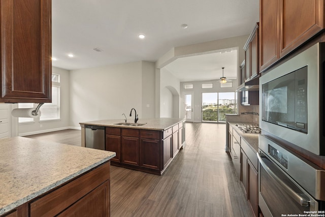 kitchen with sink, dark hardwood / wood-style floors, ceiling fan, stainless steel appliances, and a kitchen island with sink