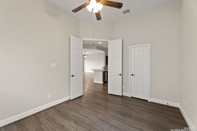 unfurnished bedroom with ceiling fan, dark hardwood / wood-style floors, and a high ceiling