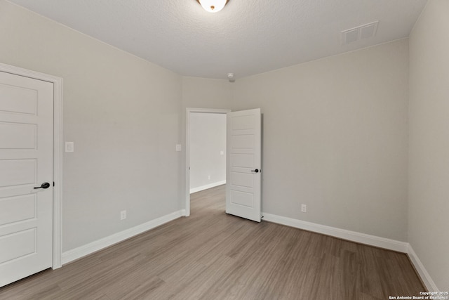 spare room with a textured ceiling and light hardwood / wood-style flooring