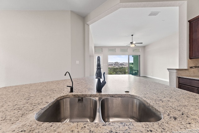 kitchen with sink, ceiling fan, dark brown cabinetry, tasteful backsplash, and light stone countertops