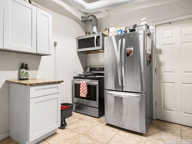 kitchen with white cabinetry, light tile patterned floors, stainless steel appliances, and stone countertops