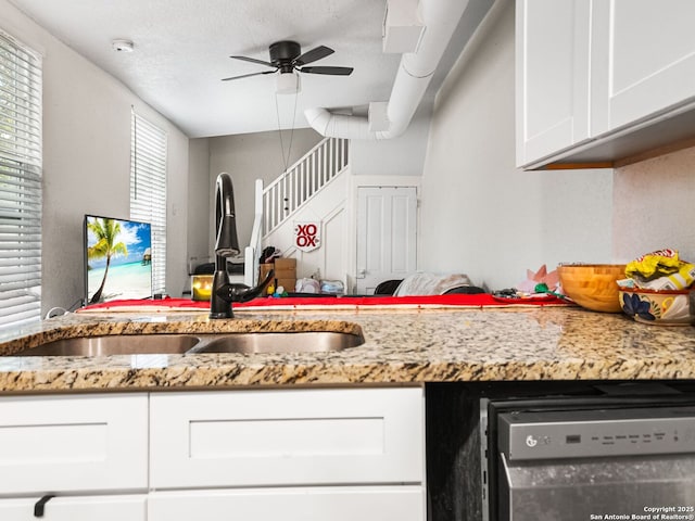 kitchen featuring sink, dishwasher, light stone counters, a textured ceiling, and white cabinets