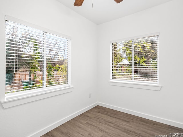 spare room featuring ceiling fan, dark hardwood / wood-style floors, and a wealth of natural light