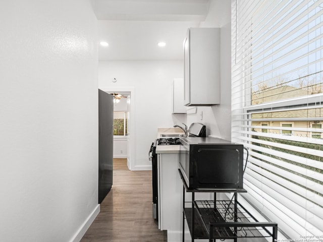 kitchen featuring sink, stainless steel fridge, white cabinetry, dark hardwood / wood-style floors, and gas range