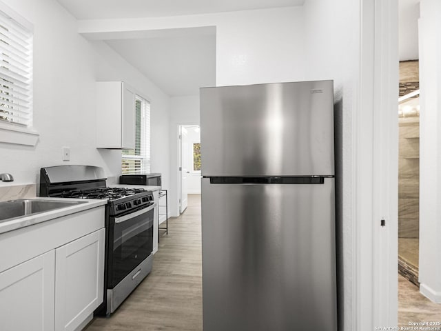 kitchen with appliances with stainless steel finishes, sink, light hardwood / wood-style flooring, and white cabinets