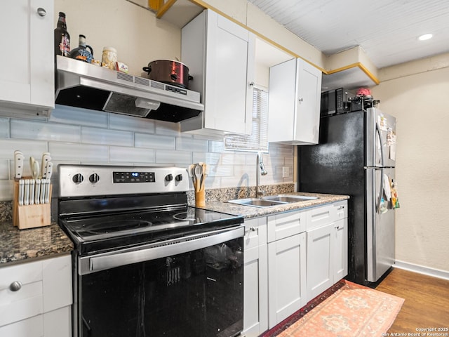 kitchen featuring appliances with stainless steel finishes, white cabinetry, sink, dark stone counters, and light wood-type flooring