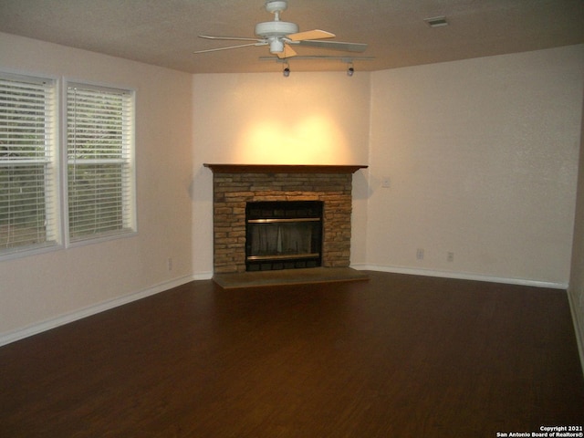 unfurnished living room featuring wood-type flooring, a stone fireplace, and ceiling fan