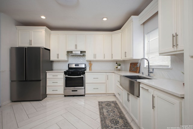 kitchen featuring gas range, white cabinetry, black fridge, and sink