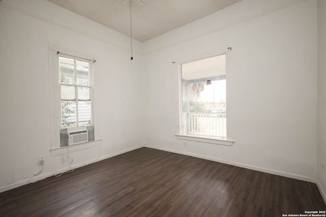 empty room with cooling unit, plenty of natural light, and dark hardwood / wood-style floors