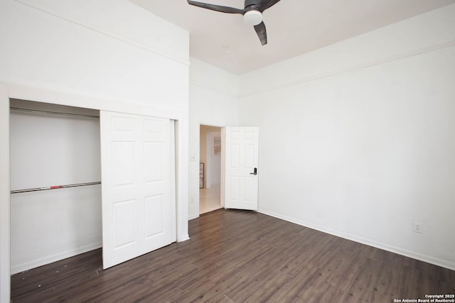 unfurnished bedroom featuring ceiling fan, dark hardwood / wood-style floors, a closet, and a high ceiling