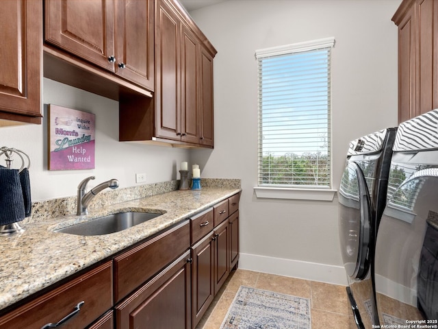 clothes washing area featuring light tile patterned flooring, cabinets, washer and clothes dryer, and sink