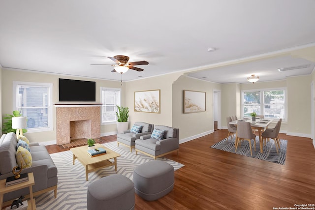 living room featuring hardwood / wood-style flooring, ornamental molding, ceiling fan, and a fireplace