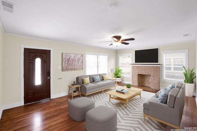 living room featuring a fireplace, dark wood-type flooring, ornamental molding, and ceiling fan