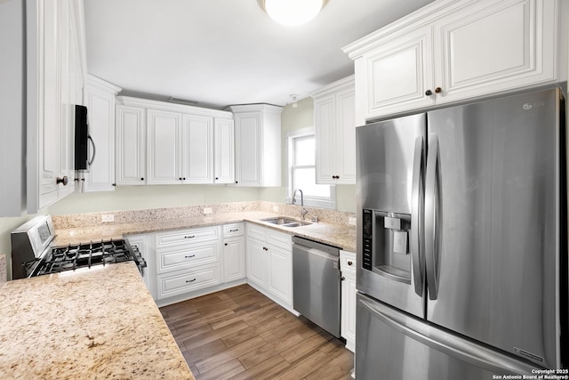 kitchen featuring light stone counters, sink, stainless steel appliances, and white cabinets