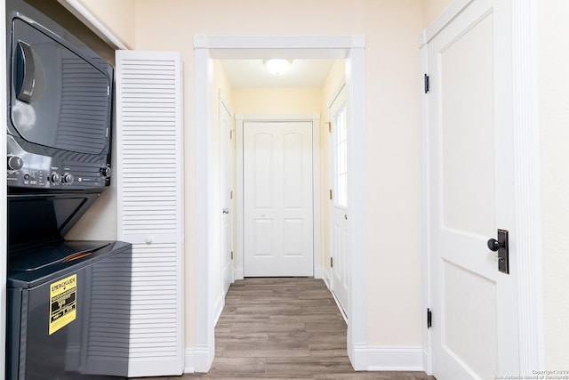 hallway featuring hardwood / wood-style flooring and stacked washer / drying machine