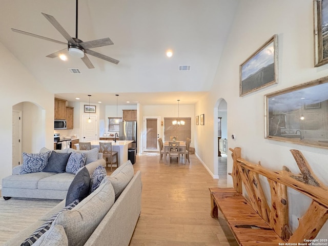 living room featuring ceiling fan, high vaulted ceiling, and light hardwood / wood-style flooring