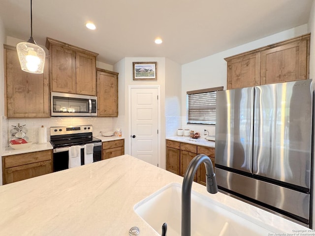 kitchen with pendant lighting, appliances with stainless steel finishes, sink, and backsplash