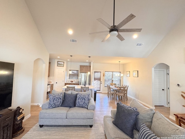 living room featuring ceiling fan, light hardwood / wood-style floors, and high vaulted ceiling