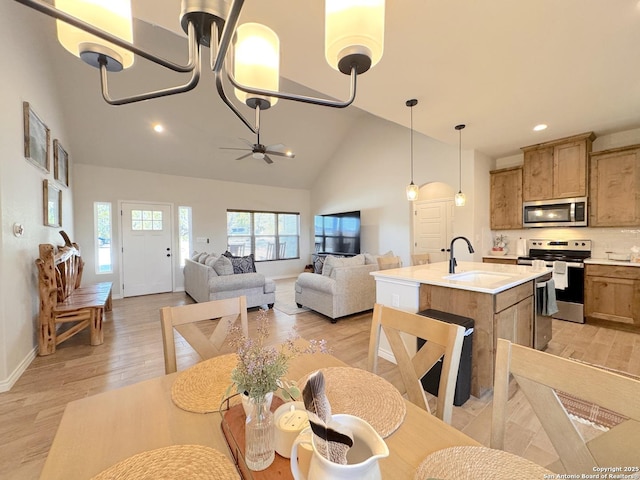 kitchen with sink, decorative light fixtures, a center island with sink, light hardwood / wood-style flooring, and stainless steel appliances