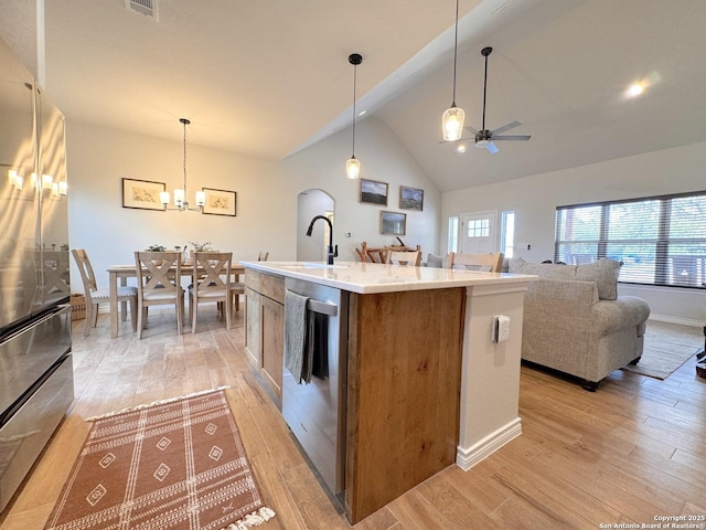 kitchen featuring stainless steel appliances, an island with sink, hanging light fixtures, and light hardwood / wood-style flooring